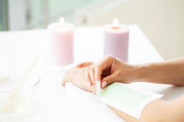 Woman doing hair removal on their hands at home in the bathroom