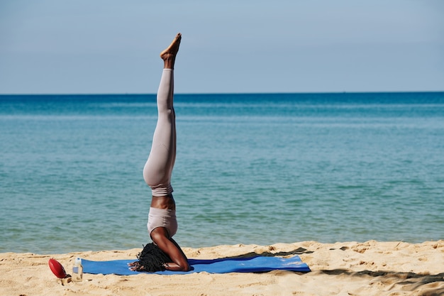 Woman doing headstand on beach