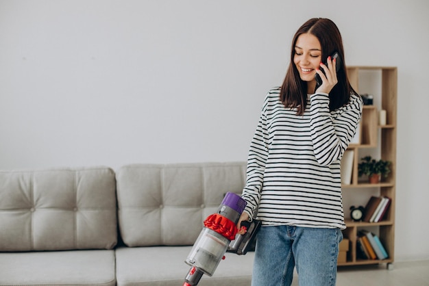 Woman doing house work with rechargeable vacuum cleaner