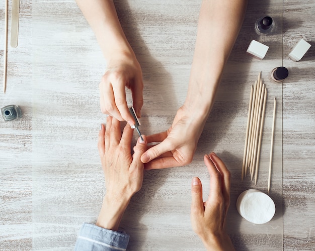 Woman doing manicure to a client indoors