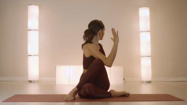 Woman doing seated spinal twist pose on mat Fit girl performing yoga in studio