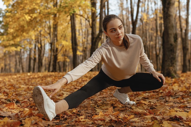 woman doing side lunge exercise and stretching legs while warming up body during running training