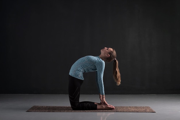 Woman doing stretching exercise camel pose or ushtrasana