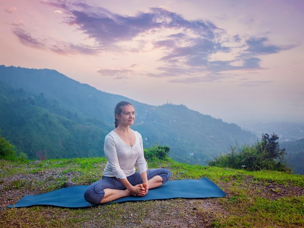 Woman doing yoga asana Baddha Konasana outdoors