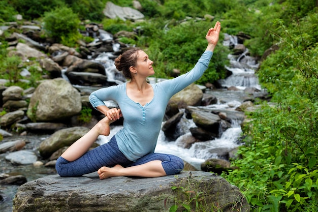 Woman doing yoga asana at tropical waterfall