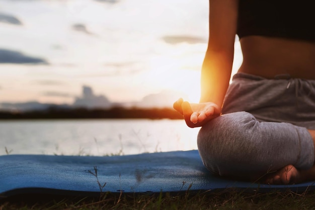 Woman doing yoga by the lake in the evening