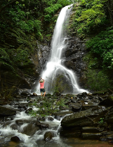 Photo woman doing yoga in front of waterfall in forest