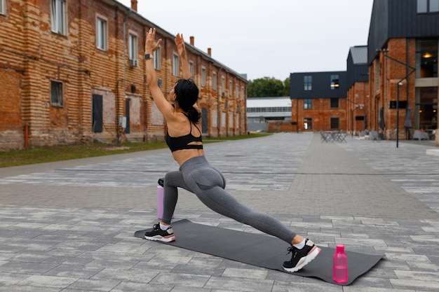 Woman doing yoga stretching exercise near brick buildings on the city street