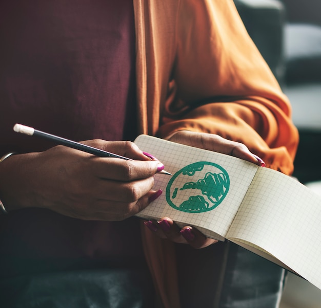 Woman drawing green globe on a notepad