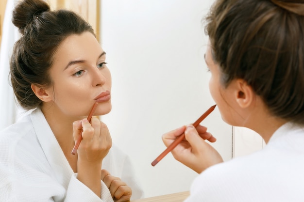 Woman drawing lip contour