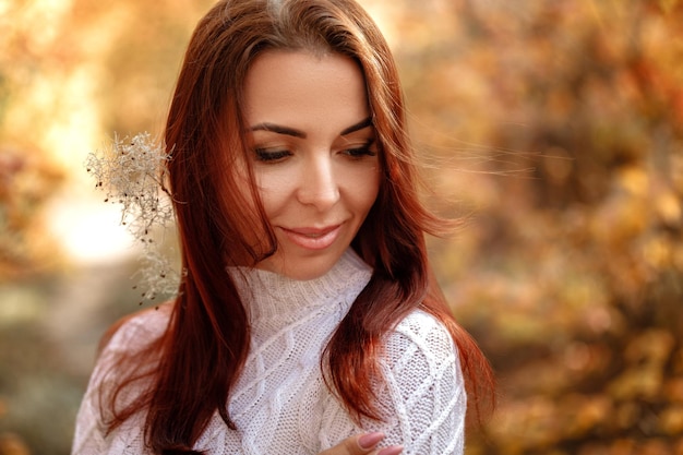 Woman in dress and hat on background of autumn foliage