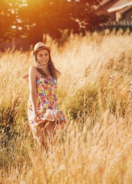 Woman in dress and hat walking in a wheat field in summer