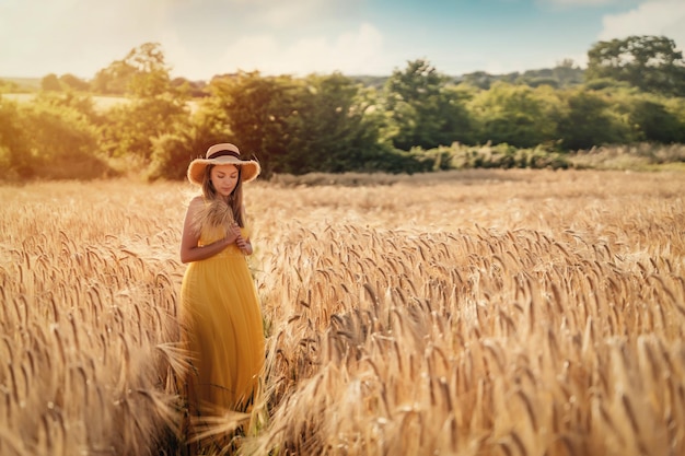 Woman in dress and hat walking in a wheat field in summer