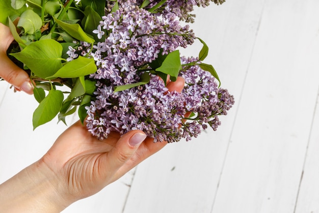 Woman in dress holding a big branch of lilac flower in her hand