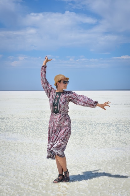 Woman in dress on a white salt lake portrait of a woman on a white salt lake woman in hat and glasses on a white salt lake