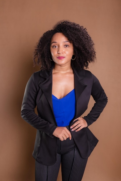 Woman dressed in black blazer standing against brown background Business woman Studio portrait