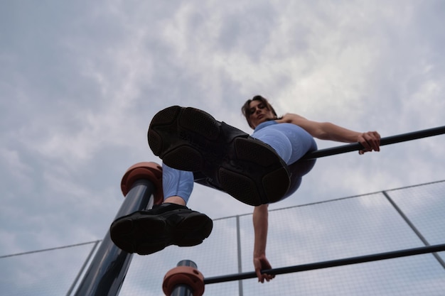 Photo woman dressed in blue athletic gear executes a pullup on a bar showcasing her upper body strength