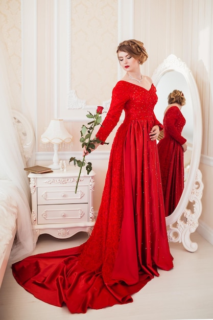 Woman dressed in red dress standing near mirror