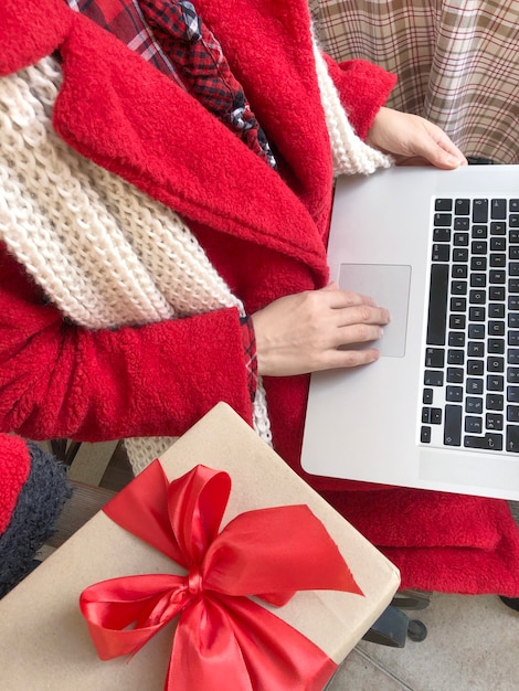 Woman dressed in red fur coat using Laptop on the eve of holidays Christmas and New Year.