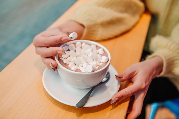 Woman dressed warm sweater, drink marshmallow with milk coffee cacao or latte