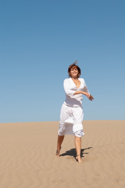 woman dressed in white enjoying the sand dunes on a sunny spring or summer day