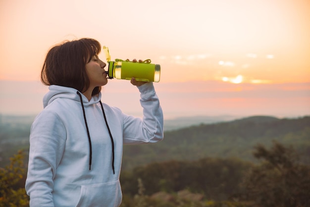 Woman drink water from the bottle after exercise on sunrise