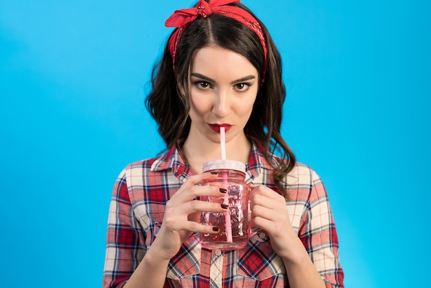 Photo the woman drinking a beverage on the blue background