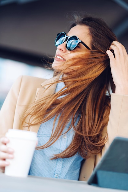 Woman drinking coffee in the street and using tablet