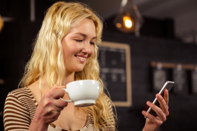 Woman drinking coffee and using smartphone