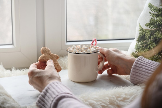 Woman drinking coffee with marshmallow and cookies gingerbread snowman