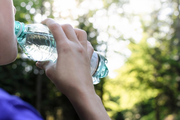 Photo woman drinking mineral water and resting while jogging in the park