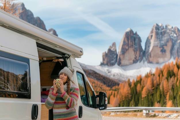 Photo woman drinking tea in camper van on the background of dolomites in autumn young caucasian woman drin