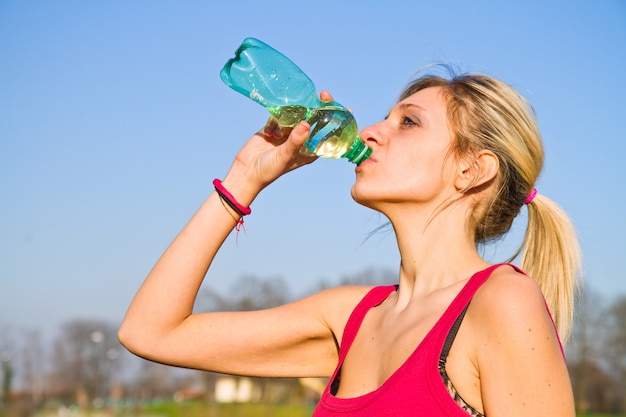 Woman drinking water from bottle after fitness sport exercise