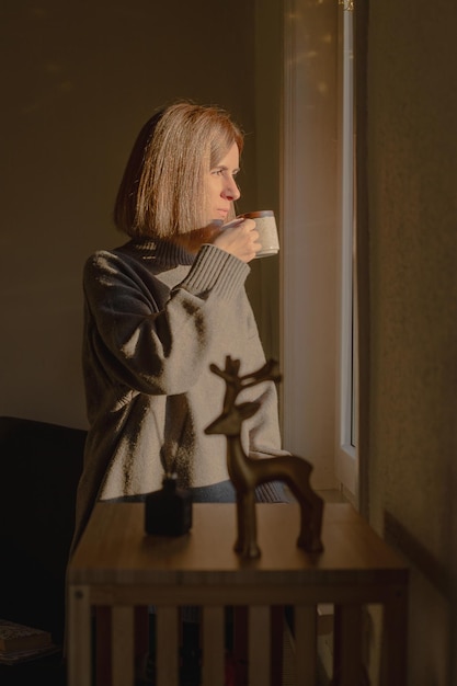 Woman drinks tee looking through window