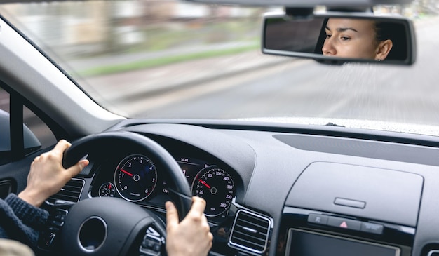 Woman drive a car reflects in back view mirror