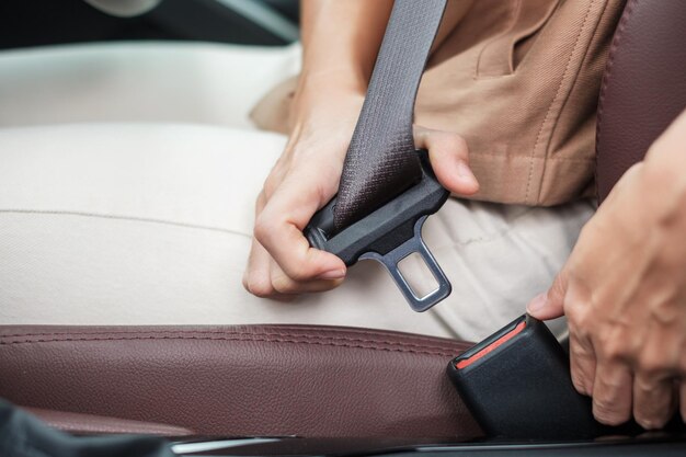 Woman driver hand fastening seat belt during sitting inside a car and driving in the road safety trip journey and transport concept