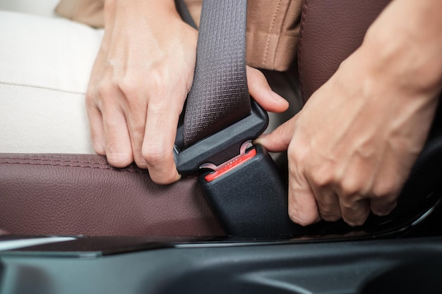 Woman driver hand fastening seat belt during sitting inside a car and driving in the road safety trip journey and transport concept