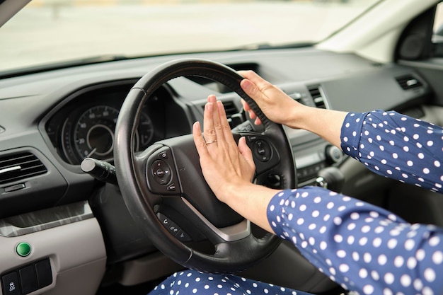 Woman driver hand honking her car horn to prevent accident Driving safety concept