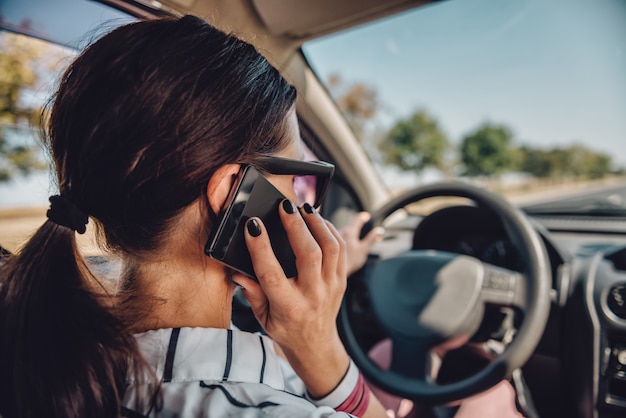 Woman driving car and talking on smart phone