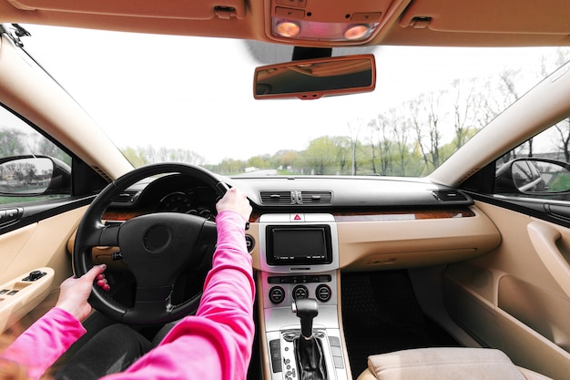 The woman driving the modern car on the asphalt road toward the sunset