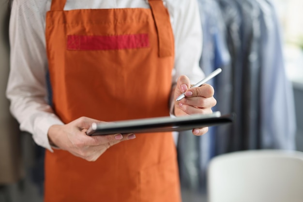 Woman dry cleaning administrator in an apron makes notes