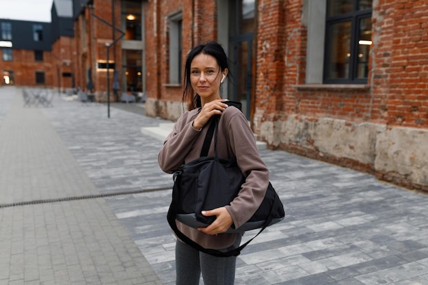 Woman in earphones with a bag on her shoulder on the way to the gym