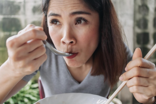 Woman eat spicy noodles with chopsticks in local street