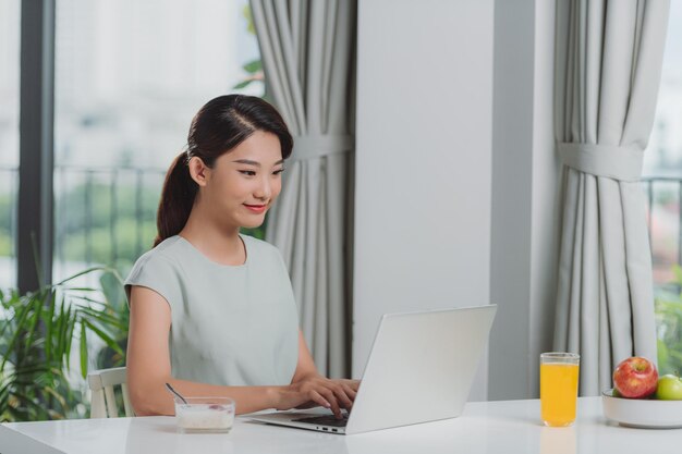 Woman eating breakfast and busy working at home