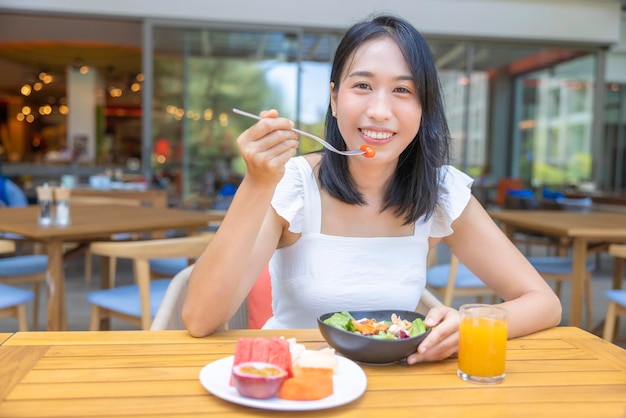 Woman eating Breakfast Fruits such as watermelon papaya melon passion fruit orange juice and coffee