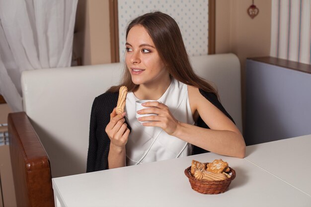 Woman eating cookies and drinking hot tea in cafe