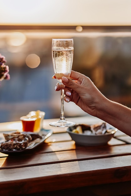 Woman eating fresh oysters and drinking chilled prosecco wine on the summer sunset Seafood delicacies