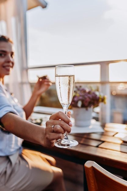 Woman eating fresh oysters and drinking chilled prosecco wine on the summer sunset Seafood delicacies