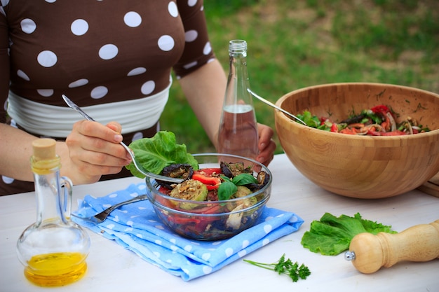 Photo a woman eating healthy mediterranean vegetable salad with grilled eggplants