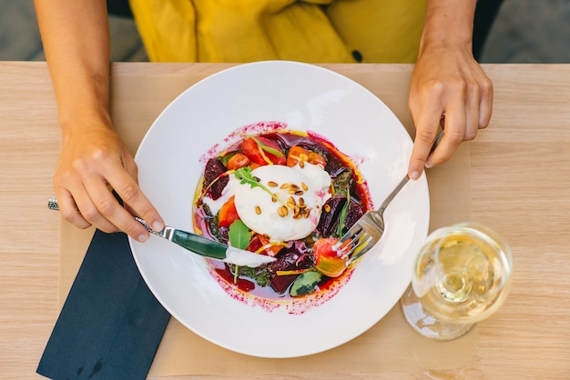 Woman eating healthy salad with burrata cheese, arugula and beetroot salad